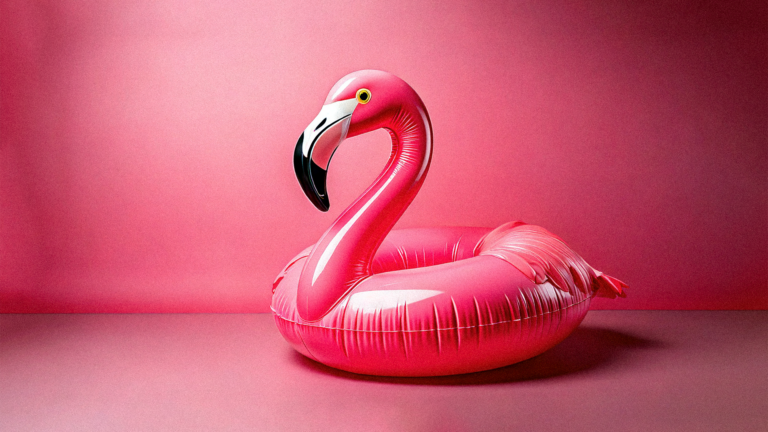 A large inflatable pink flamingo float sits on a smooth, pink surface with a pink gradient background. The float has a glossy finish and a cartoon-like appearance, evoking a fun, summery vibe.
